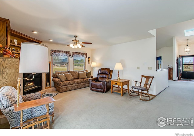 carpeted living room featuring ceiling fan and a fireplace