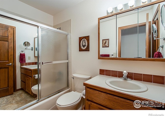 full bathroom with combined bath / shower with glass door, vanity, and toilet