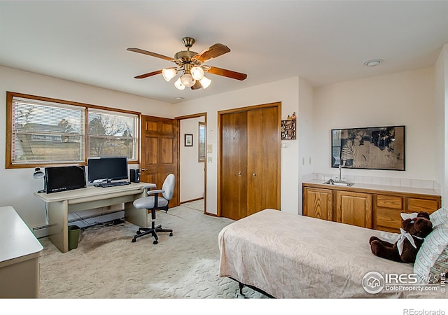 bedroom featuring ceiling fan, a baseboard heating unit, light carpet, and a closet