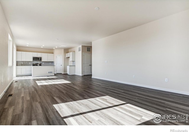 unfurnished living room with dark wood-type flooring