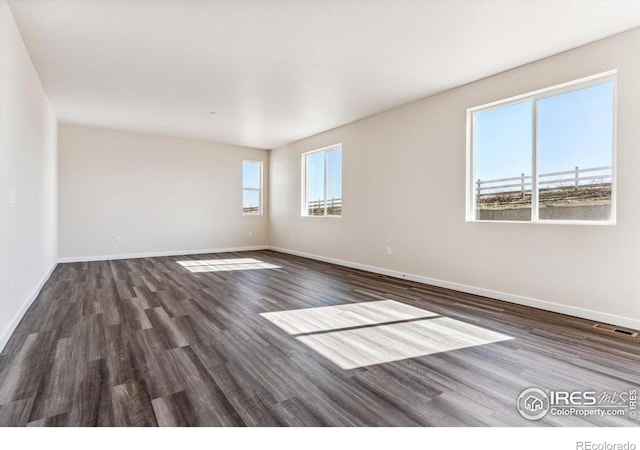 empty room featuring a healthy amount of sunlight and dark hardwood / wood-style floors