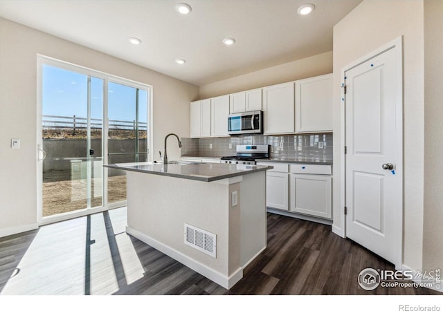 kitchen featuring stainless steel appliances, white cabinetry, dark hardwood / wood-style floors, and an island with sink