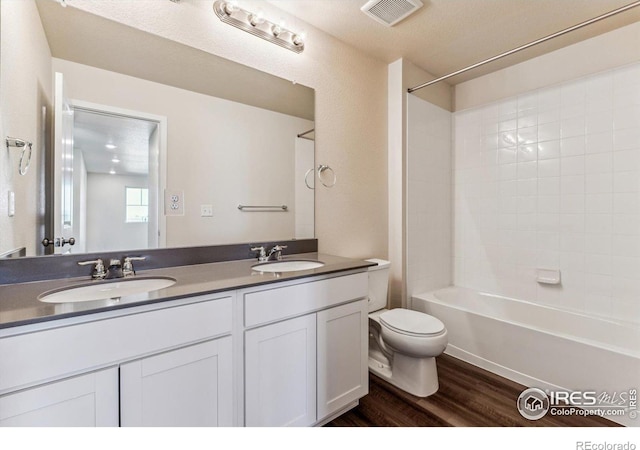 full bathroom featuring hardwood / wood-style floors, a textured ceiling, toilet, shower / tub combination, and vanity