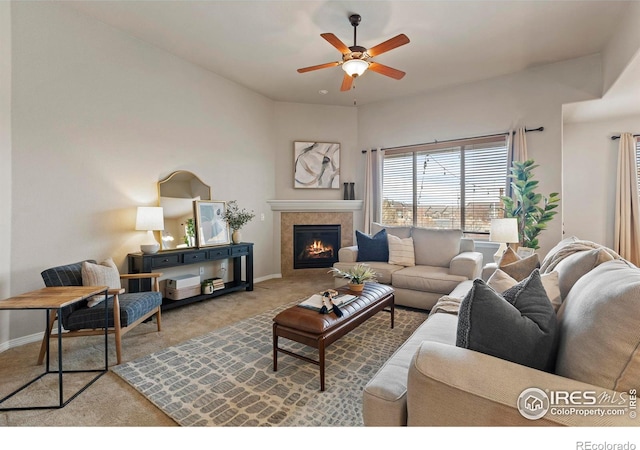 living room featuring a tile fireplace, ceiling fan, and light carpet