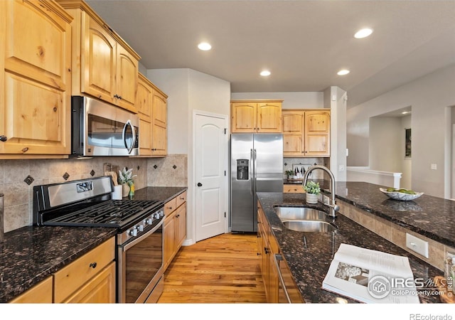 kitchen with sink, stainless steel appliances, dark stone counters, and backsplash