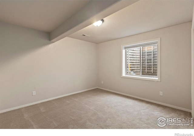 empty room with light colored carpet and beamed ceiling