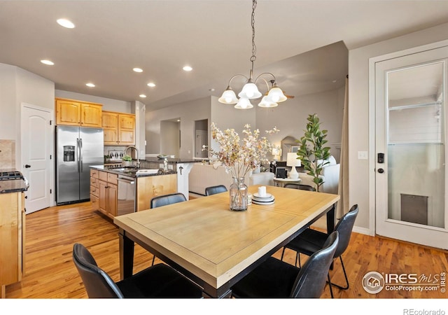 dining room with a notable chandelier, light hardwood / wood-style flooring, and sink