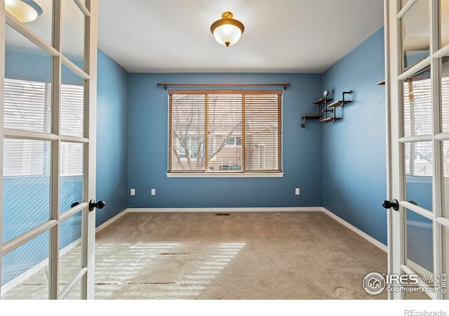 empty room featuring french doors and carpet