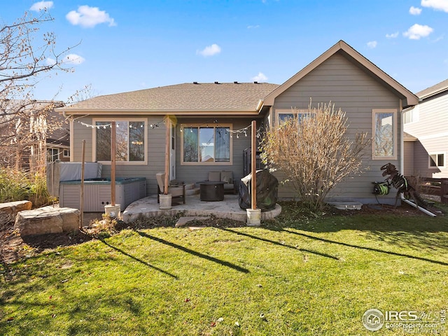 rear view of house featuring a hot tub, a patio, and a lawn