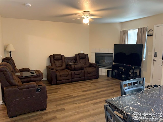 living room featuring ceiling fan, wood-type flooring, and a tile fireplace