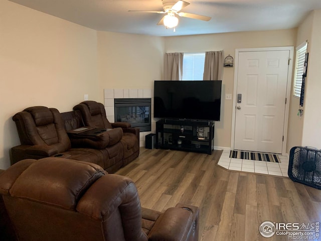 living room featuring hardwood / wood-style flooring, ceiling fan, and a tiled fireplace