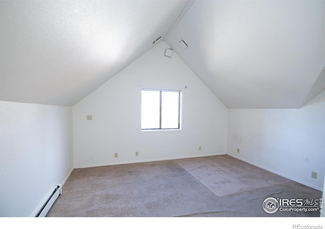 additional living space with light carpet, vaulted ceiling, and a baseboard heating unit