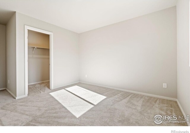 unfurnished bedroom with a walk in closet, light carpet, and a closet