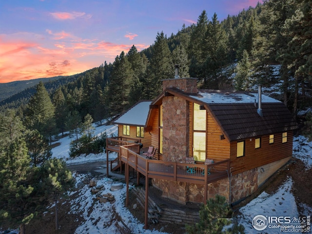 snow covered rear of property featuring a deck with mountain view