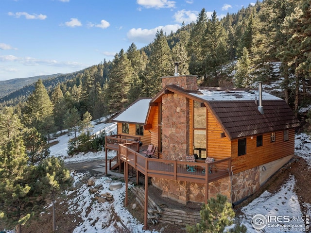 snow covered rear of property with a wooden deck