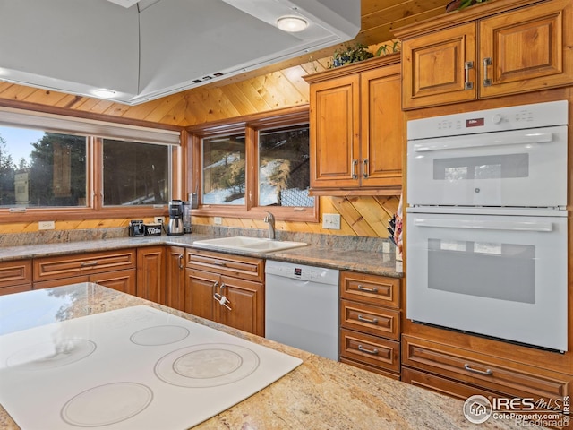 kitchen with plenty of natural light, wood walls, white appliances, and sink