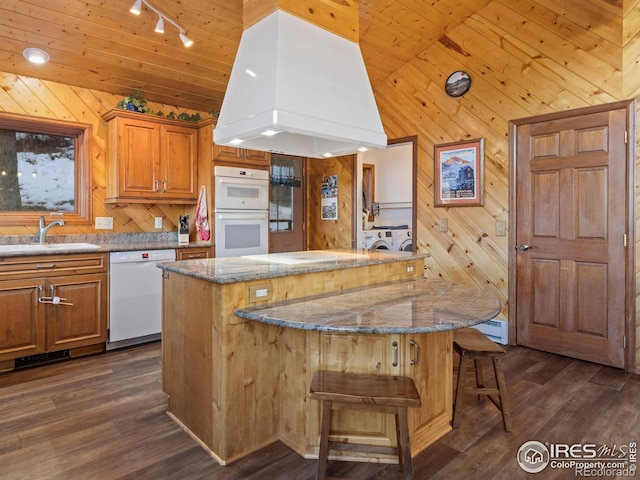 kitchen featuring custom exhaust hood, a center island, white appliances, sink, and wooden walls