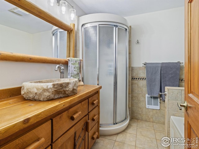 bathroom with tile patterned floors, vanity, an enclosed shower, and tile walls