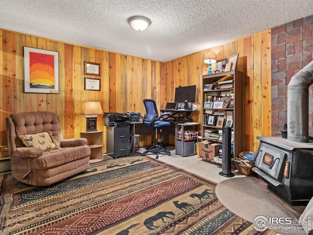 carpeted office space featuring a textured ceiling, a wood stove, and wooden walls