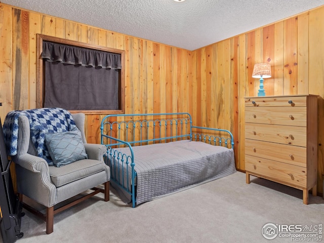 carpeted bedroom with a textured ceiling and wooden walls