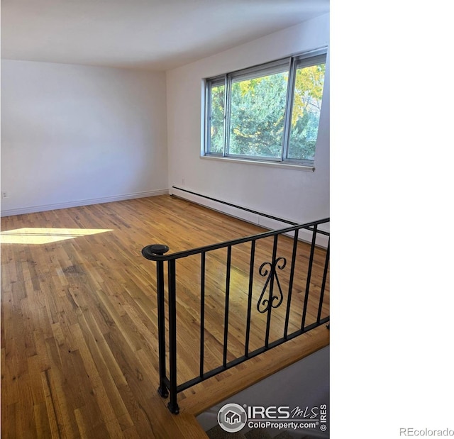 stairway with hardwood / wood-style floors and a baseboard radiator