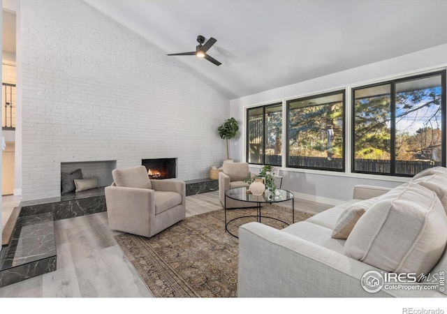 living room with ceiling fan, a large fireplace, high vaulted ceiling, brick wall, and wood-type flooring