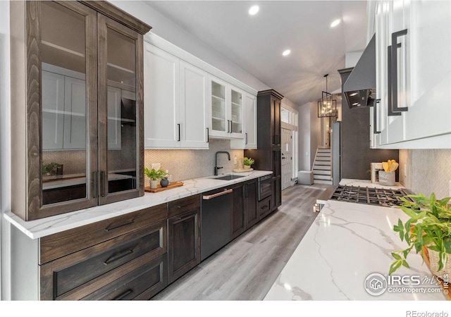 kitchen with dishwasher, sink, light wood-type flooring, decorative light fixtures, and white cabinetry