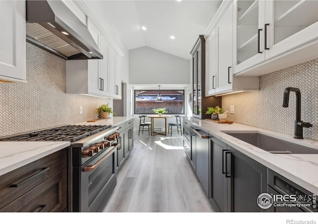 kitchen with stainless steel range, wall chimney exhaust hood, sink, decorative backsplash, and white cabinets