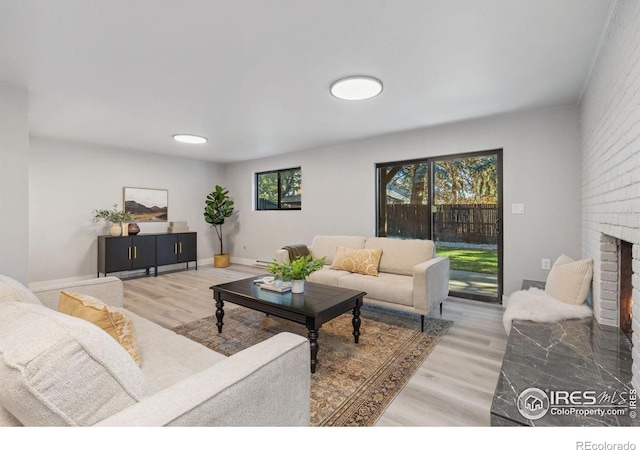 living room with hardwood / wood-style flooring, a brick fireplace, and brick wall