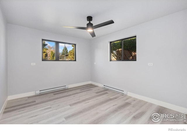 empty room with light hardwood / wood-style floors, baseboard heating, and plenty of natural light