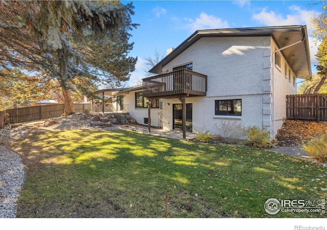 back of property featuring a yard, a balcony, and a patio