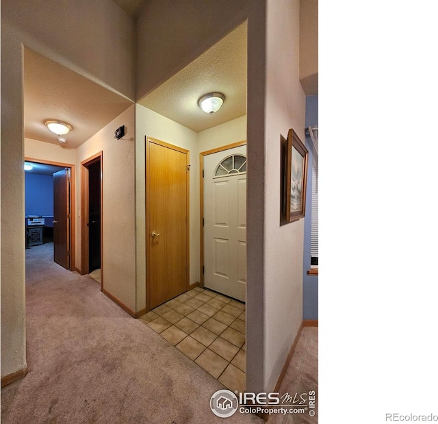 hall with light colored carpet and a textured ceiling