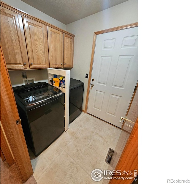 washroom featuring cabinets, a textured ceiling, and separate washer and dryer