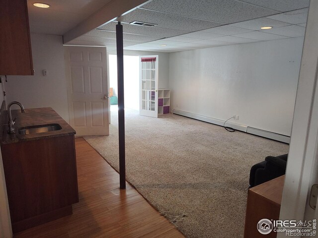 basement with hardwood / wood-style floors, a baseboard heating unit, and sink