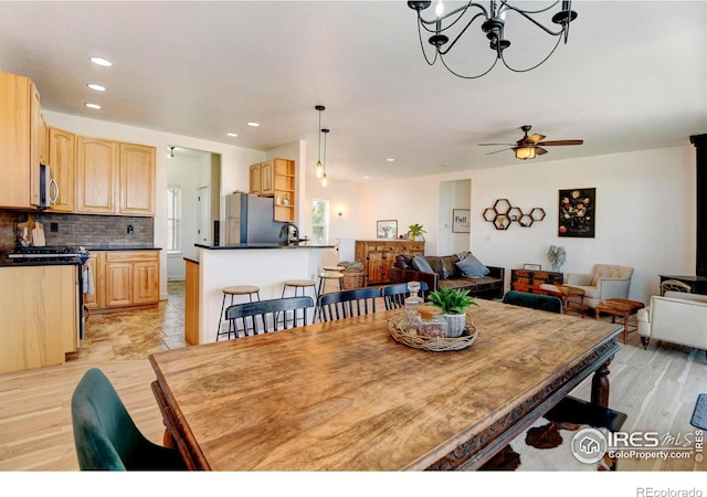 dining area featuring light hardwood / wood-style floors, ceiling fan with notable chandelier, and sink