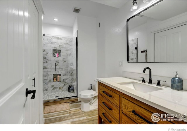 bathroom featuring toilet, vanity, and a shower with door