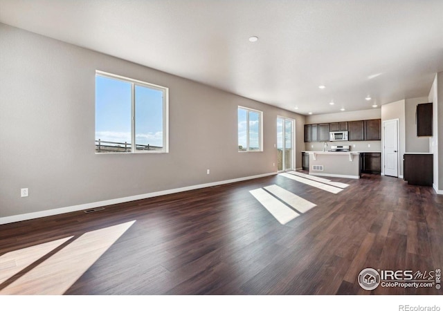 unfurnished living room featuring a healthy amount of sunlight and dark hardwood / wood-style flooring