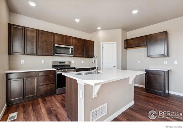 kitchen with a center island with sink, sink, dark hardwood / wood-style floors, appliances with stainless steel finishes, and dark brown cabinetry