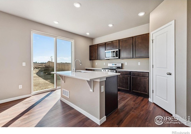 kitchen with dark hardwood / wood-style flooring, an island with sink, stainless steel appliances, and sink