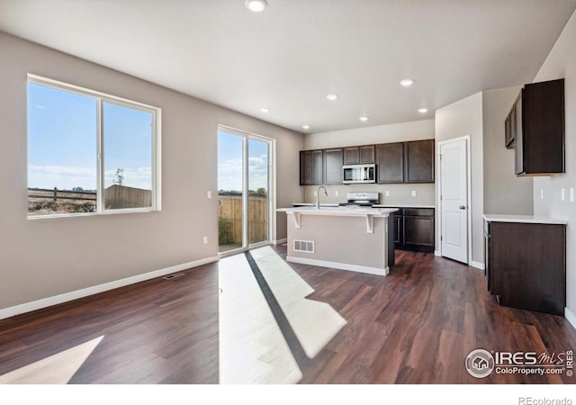 kitchen featuring sink, range, dark wood-type flooring, and a kitchen island with sink