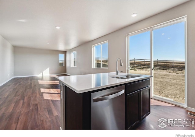 kitchen with stainless steel dishwasher, sink, an island with sink, and dark wood-type flooring