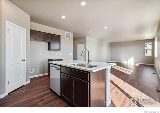 kitchen featuring sink, dark wood-type flooring, stainless steel dishwasher, dark brown cabinets, and a center island with sink