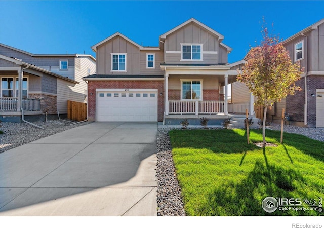 view of front of property with covered porch, a garage, and a front yard