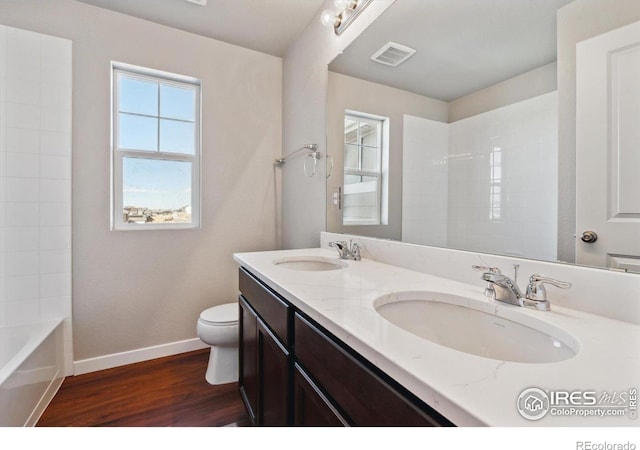 full bathroom featuring tiled shower / bath, hardwood / wood-style floors, vanity, and toilet