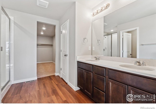 bathroom featuring wood-type flooring, vanity, and an enclosed shower