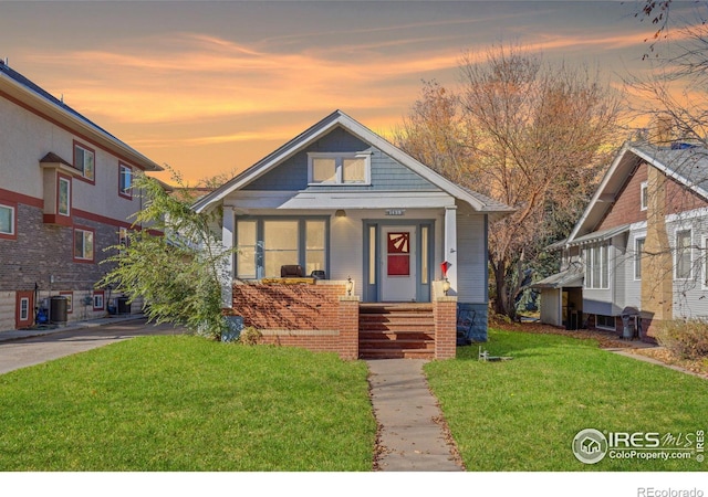 bungalow featuring a lawn, a porch, and cooling unit