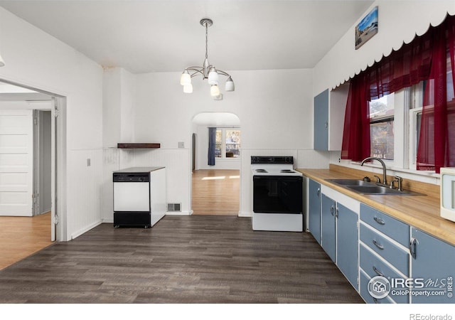 kitchen featuring white appliances, dark wood-type flooring, an inviting chandelier, sink, and hanging light fixtures