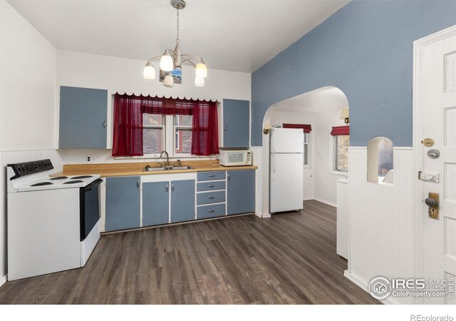 kitchen with a wealth of natural light, dark hardwood / wood-style floors, white appliances, and blue cabinets