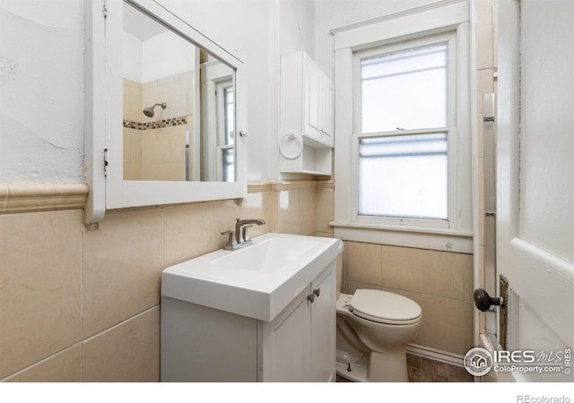 bathroom featuring vanity, toilet, and tile walls