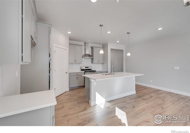 1815 Chaffee Crest Dr, Berthoud, CO 80513 - kitchen with wall chimney exhaust hood, stainless steel range, a kitchen island with sink, decorative light fixtures, and light hardwood / wood-style floors